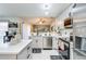 Open-concept kitchen featuring stainless steel appliances, white cabinetry, and a view into the living area at 402 Bramble Way, Minneola, FL 34715