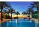 Stunning community pool area surrounded by palm trees and serene twilight sky at 7697 Heritage Crossing Way # 302, Reunion, FL 34747