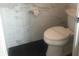 Modern toilet with marble-style tiled walls and black flooring at 7697 Heritage Crossing Way # 302, Reunion, FL 34747