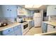 Charming blue kitchen featuring white appliances, cabinets, white countertops, and accent lighting at 1 Oceans West Blvd # 3B4, Daytona Beach, FL 32118