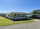 Inviting exterior view of a well-kept mobile home with lush lawn and a convenient carport at 114 Caladium St, Leesburg, FL 34748