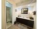 Bathroom featuring a vanity with a mirror, decorative wallpaper, and a doorway view of a shower stall at 123 Pyracantha Ln, Leesburg, FL 34748