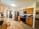 Bright kitchen with wood cabinets, stainless steel appliances, and wood grain vinyl flooring at 123 Pyracantha Ln, Leesburg, FL 34748