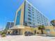 Stunning exterior view of a yellow oceanfront condominium under a bright blue sky at 1909 S Atlantic Ave # 703, Daytona Beach, FL 32118