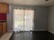 Living room with hardwood floors, a sliding glass door with sheer curtains, and dated cabinets at 24047 Ermine Rd, Astor, FL 32102