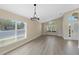 Bright living room with hardwood floors, a modern light fixture, and arched windows allowing natural light at 9324 Pecky Cypress Way, Orlando, FL 32836