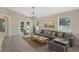 Staged living room with hardwood floors, neutral walls, grey sofa and many windows at 9324 Pecky Cypress Way, Orlando, FL 32836