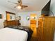 This bedroom features wood floors, a ceiling fan, a large dresser, and a door to the ensuite bathroom at 106 Palo Verde Dr, Leesburg, FL 34748