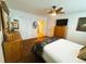 This bedroom features wood floors, a ceiling fan, a large dresser, and a door to the ensuite bathroom at 106 Palo Verde Dr, Leesburg, FL 34748