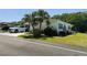 Well-maintained single-story home featuring a carport, landscaped yard with mature trees, and fresh green grass at 106 Palo Verde Dr, Leesburg, FL 34748