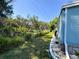A backyard with a manicured lawn, mature trees, and home with blue siding at 121 Bougainvillea Dr, Leesburg, FL 34748