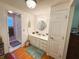 A well-lit bathroom featuring a vanity with a countertop, cabinets, a mirror, and a shower area at 121 Bougainvillea Dr, Leesburg, FL 34748