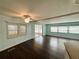 Light-filled living room with dark wood flooring, ceiling fan, and sliding door access to the screened-in porch at 139 Royal Palm Dr, Leesburg, FL 34748