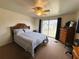 Carpeted primary bedroom with a ceiling fan, dresser, mirror and exterior views at 141 Aspen Cir, Leesburg, FL 34748