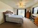 Carpeted primary bedroom with a ceiling fan, dresser, mirror and exterior views at 141 Aspen Cir, Leesburg, FL 34748
