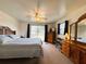 Carpeted primary bedroom with a ceiling fan, dresser, mirror and exterior views at 141 Aspen Cir, Leesburg, FL 34748