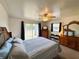 Carpeted primary bedroom with a ceiling fan, dresser, mirror and exterior views at 141 Aspen Cir, Leesburg, FL 34748