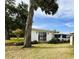 Cozy home featuring a well-manicured lawn, mature trees, and a charming exterior at 141 Aspen Cir, Leesburg, FL 34748