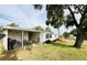 Charming home featuring an outdoor patio, complemented by lush lawn and mature trees for relaxing outdoor living at 141 Aspen Cir, Leesburg, FL 34748