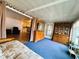 Sunroom featuring blue carpet, futon, hutch, and sliding door access at 141 Aspen Cir, Leesburg, FL 34748