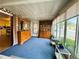 View of sunroom with furnishings, windows, blue carpet, with attached glimpse of yellow kitchen at 141 Aspen Cir, Leesburg, FL 34748