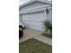 Damaged white garage door of a single-Gathering home with cars parked in the driveway at 1484 Avleigh Se Cir, Orlando, FL 32824