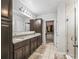 Bright bathroom featuring granite countertops, dual sinks, walk-in shower, and access to a spacious closet at 1936 Bell Creek Loop, Fruitland Park, FL 34731