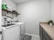 Well-organized laundry room with washer, dryer, overhead shelving, and stylish decor at 1936 Bell Creek Loop, Fruitland Park, FL 34731