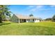 Expansive backyard view of a single story home with a covered patio and lush green lawn at 2561 Rogers Rd, Lakeland, FL 33812