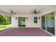 A covered patio with brick flooring, ceiling fans, and sliding glass doors lead to the yard at 2561 Rogers Rd, Lakeland, FL 33812