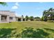 Large backyard with luscious grass with the back of the home in the distance at 34 Misty Meadow Ln, Mulberry, FL 33860