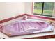 A jacuzzi style tub with pink marble next to a window at 34 Misty Meadow Ln, Mulberry, FL 33860