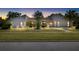 Charming one-story home with well-manicured lawn and mature landscaping at dusk at 34 Misty Meadow Ln, Mulberry, FL 33860