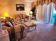 Relaxing living room boasts plush patterned sofas, a glass-topped coffee table, and access to the outdoors at 4613 Eaglet Ln, Kissimmee, FL 34746