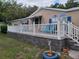 Inviting home exterior showcasing a white deck with white railings, blue shutters, and decorative yard features at 4814 Myrtle View N Dr, Mulberry, FL 33860