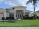 Inviting front entrance featuring glass double doors, decorative shrubbery, and a meticulously maintained lawn at 7157 Hazeltine Cir, Lakeland, FL 33810
