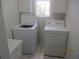 Efficient laundry room with white washer, dryer, cabinets, and window for natural light at 7157 Hazeltine Cir, Lakeland, FL 33810