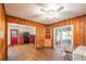 Dining room with wood paneled walls leading to kitchen with red cabinets and access to screened in porch at 727 Se 12Th St, Ocala, FL 34471