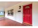 A red door welcomes visitors to a front porch with red tile and a hanging vintage light fixture at 727 Se 12Th St, Ocala, FL 34471