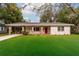 Charming single-story home features a bright red front door, brick column accents and a lush green lawn at 727 Se 12Th St, Ocala, FL 34471