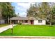 Charming single-story home features a bright red front door, brick column accents and a lush green lawn at 727 Se 12Th St, Ocala, FL 34471