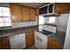 Well-lit kitchen featuring white appliances, wooden cabinets, and views to living area at 1000 S Semoran Blvd # 306, Winter Park, FL 32792