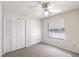 Bright bedroom featuring a window, ceiling fan, carpet, and ample closet space with white bi-fold doors at 10441 Sw 54Th Ct, Ocala, FL 34476