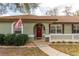 Close up of the entry featuring a red door, arched window, manicured landscaping, and stone accents at 10441 Sw 54Th Ct, Ocala, FL 34476