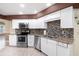 Modern kitchen with white cabinets, granite countertops, and stainless steel appliances, enhanced by a mosaic backsplash at 10441 Sw 54Th Ct, Ocala, FL 34476
