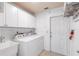Functional laundry area featuring white appliances, cabinets, and a utility sink, all within a bright and efficient space at 10441 Sw 54Th Ct, Ocala, FL 34476