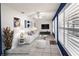 Staged living room with modern white furniture, bright windows, and a ceiling fan above tiled floors at 10441 Sw 54Th Ct, Ocala, FL 34476