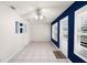Bright living room featuring tile floors, a modern ceiling fan, and white walls contrasted by a deep blue accent wall at 10441 Sw 54Th Ct, Ocala, FL 34476