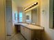 Bathroom featuring under-sink storage, illuminated mirror, and marble-style flooring and surfaces at 106 Pyracantha Ln, Leesburg, FL 34748