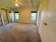 Large bedroom featuring tan carpet, sliding glass door closet and 2 windows with dark shades at 106 Pyracantha Ln, Leesburg, FL 34748